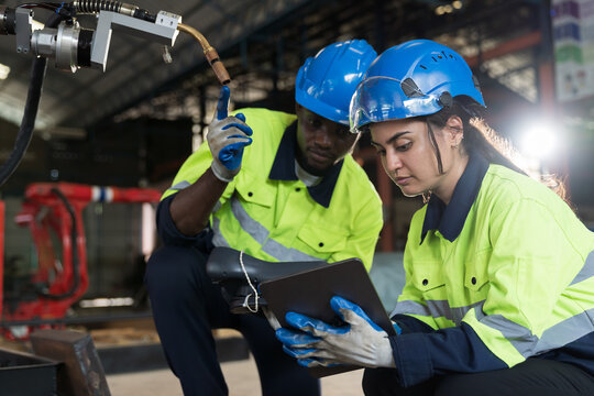 Male and female engineer repair autonomous robotics arm. Group of technician maintenance and control robotics arm in factory