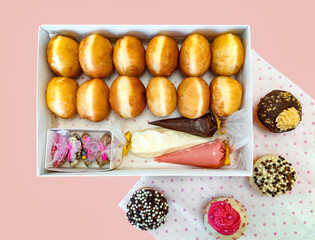 Top view of a box with donuts on pink concrete background. Hanukkah sweet food doughnuts sufganiyot .Jewish holiday Hanukkah concept. 
