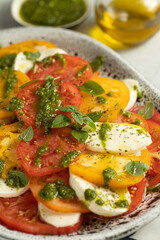 Close up of Caprese salad with yellow and red tomato on browm background. Italian cuisine.