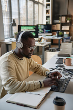 Young Black software developer working on laptop in office of startup company