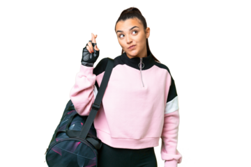 Young sport woman with sport bag over isolated chroma key background with fingers crossing and wishing the best