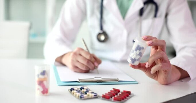 The doctor holds the medicine and writes a prescription, close-up. Medical prete treatment, slowmotion