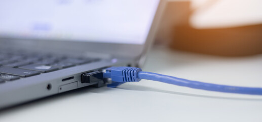 close up on laptop port interface with blue an cable connected to transfer bandwidth and usage internet data to global network for internet technology transmission service concept