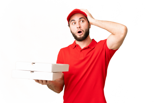 pizza delivery man with work uniform picking up pizza boxes over isolated chroma key background doing surprise gesture while looking to the side