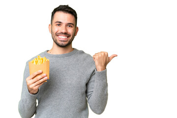 Young caucasian man holding fried chips over isolated chroma key background pointing to the side to present a product - obrazy, fototapety, plakaty