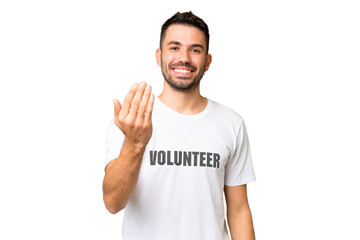 Young volunteer caucasian man over isolated chroma key background inviting to come with hand. Happy that you came