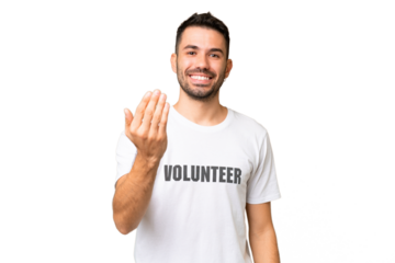 Young volunteer caucasian man over isolated chroma key background inviting to come with hand. Happy that you came