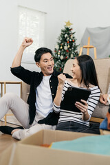 Successful young couple is moving to a nice new place, around boxes with their belongings. The room is very bright and bright, they are wearing casual clothes.