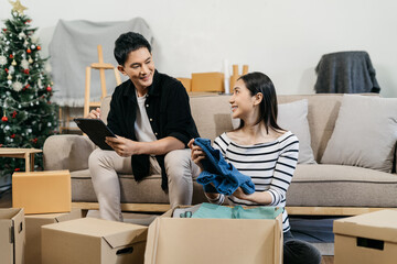 Young couple relaxing sitting on the floor around cardboard boxes at home, smiling happy moving to a new house.