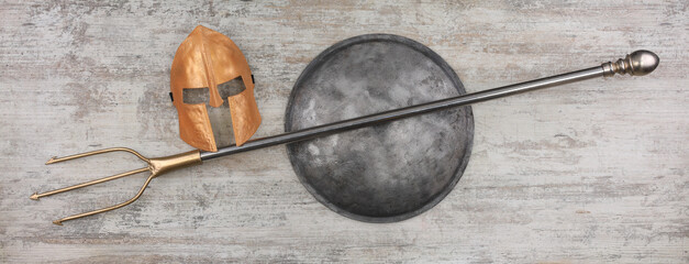 medieval trident and iron shield on wooden background