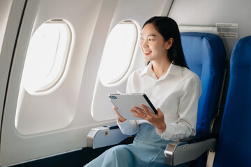 Young Asian executive excels in first class, multitasking with digital tablet, laptop and smartphone. Travel in style, work