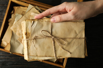 Old love letters in human hands, on a dark background.