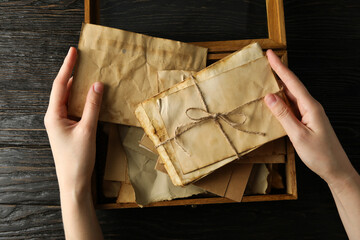 Old love letters in human hands, on a dark background.