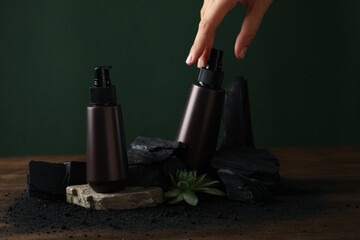 A bottle with natural, charcoal cosmetics on a green background.