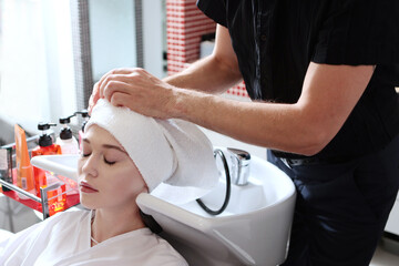 A towel is tied over wet hair. A girl washes her hair in a beauty salon.