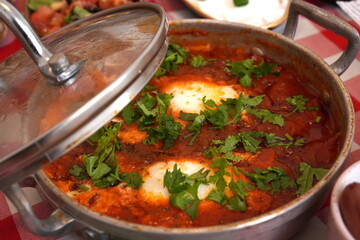 shakshuka poached eggs in a delicious chunky tomato and bell pepper sauce made in a pot with parsley sprinkled on top