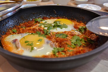 shakshuka poached eggs in a delicious chunky tomato and bell pepper sauce made in a pot with parsley sprinkled on top