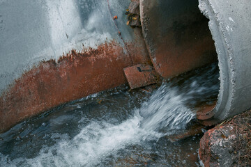 A sewage pipe drains toxic wastewater into a river, causing environmental pollution and ecological damage.