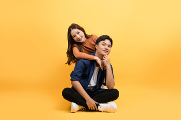 Two good looking Asian couples sit and relax on yellow background.