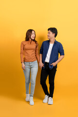 Full view of young Asian couple walking holding hands on blue background.