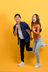 Happy smiling Asian couple with surprise isolated on yellow studio background.