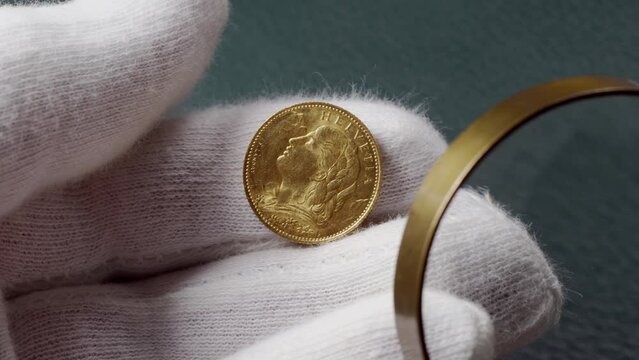 Swiss gold coin ten francs close-up in gloved hand