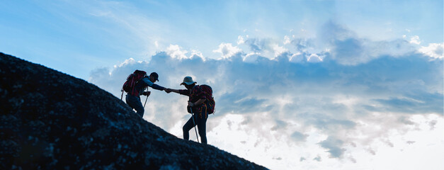 Silhouette of Asian Male and female hikers climbing up mountain cliff and one of them giving helping hand with friend at sunset, People helping, Asia couple hiking help each other concept. - obrazy, fototapety, plakaty