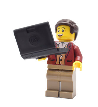 Lego minifigure of businessman or boss with laptop or notebook. Editorial illustrative image of popular plastic toy constructor.