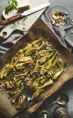 Delicious roasted fennel with nuts on baking sheet on kitchen table with utensils , top view