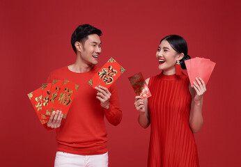 Happy Chinese new year. Asian couple wearing red clothing holding angpao or red packet monetary...
