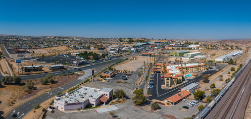 Aerial view of a Barstow U.S. town blending modern and traditional architecture, with earth-toned buildings, red-tiled roofs, and a clear blue sky in a desert setting. - obrazy, fototapety, plakaty