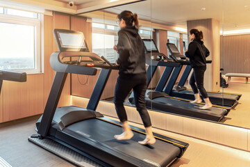 An Asian woman runs in the gym to exercise her body