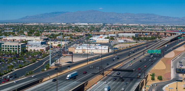 Aerial view of a southwestern U.S. cityscape with a busy highway interchange, modern buildings, mountain backdrop, and clear blue skies in Las Vegas, USA. - Powered by Adobe
