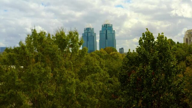 Aerial shot slowly rising above the trees to reveal the King and Queen towers in Atlanta.