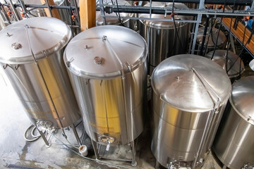 High angle view of some shiny metal tanks and pipework in a beer processing facility for the...