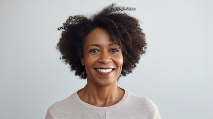 Portrait of a black mature woman looking at the camera with a smile on a white bright studio background - obrazy, fototapety, plakaty