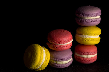 Colored macaroons. Delicious sweet colorful French desserts on black background. Copy space.