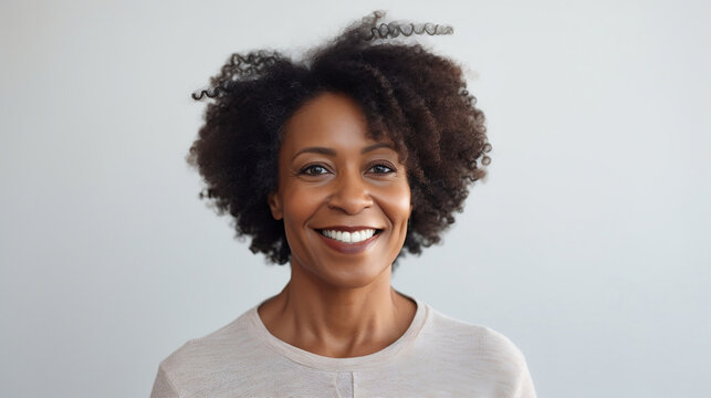 Portrait Of A Black Mature Woman Looking At The Camera With A Smile On A White Bright Studio Background