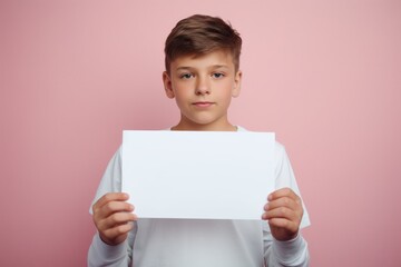 a handsome boy holding a blank placard sign poster paper for mock up in his hands