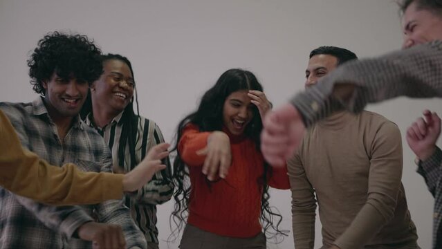 Young diverse multiracial multiethnic friends dancing moving celebrating birthday or friendship anniversary. Happy excited cheerful friends celebrate success and victory