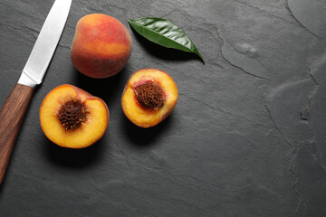 Delicious juicy peaches, leaf and knife on black textured table, flat lay. Space for text