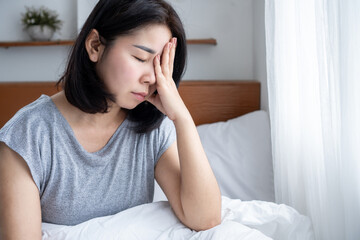 mental health concept with stressed Asian woman sitting in bed with sad mood