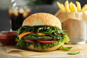 Tasty vegetarian burger with spinach cutlet, cheese and vegetables served on white table, closeup