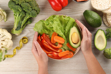 Healthy diet. Woman with fresh vegetables and measuring tape at light wooden table, top view