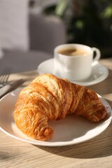 Delicious fresh croissant served with coffee on wooden table