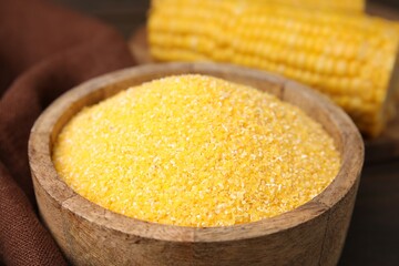 Raw cornmeal in bowl on table, closeup