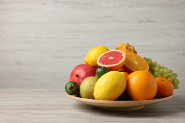 Different ripe fruits on light wooden table, space for text