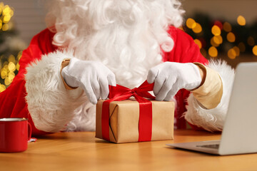Obraz na płótnie Canvas Santa Claus decorating Christmas gift with ribbon at home, closeup