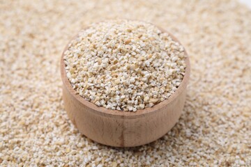 Wooden bowl on raw barley groats, closeup