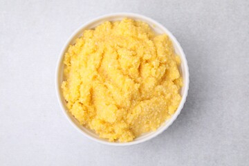 Tasty cornmeal in bowl on light gray table, top view